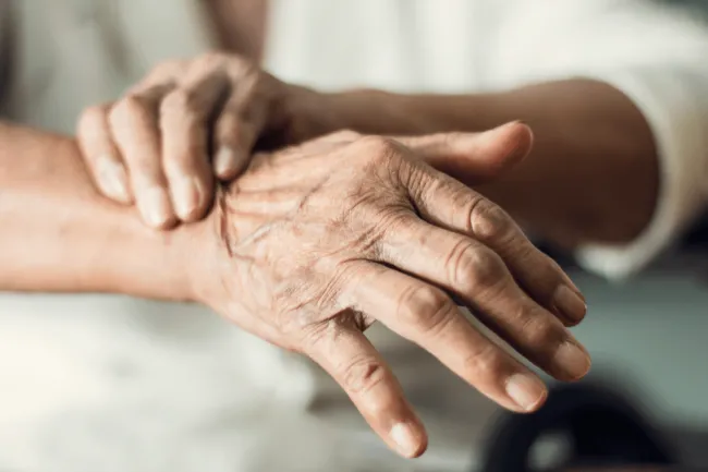 Close up hands of senior elderly woman patient suffering from pakinson's desease symptom