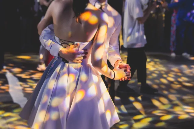 Teenagers dancing at prom night under colorful lights