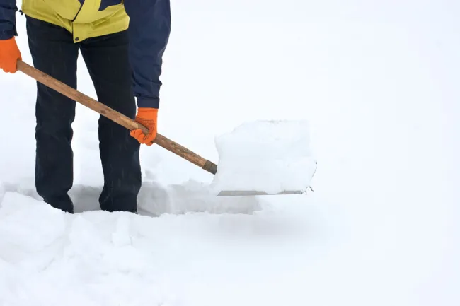 Snowstorm Shopping: Who’s Liable in a Slip and Fall? - A man shoveling a snow